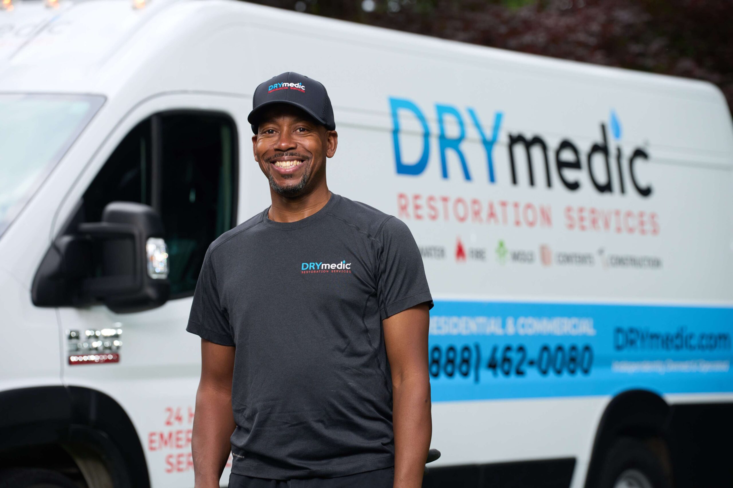 A man in a hat in front of a DRYmedic van